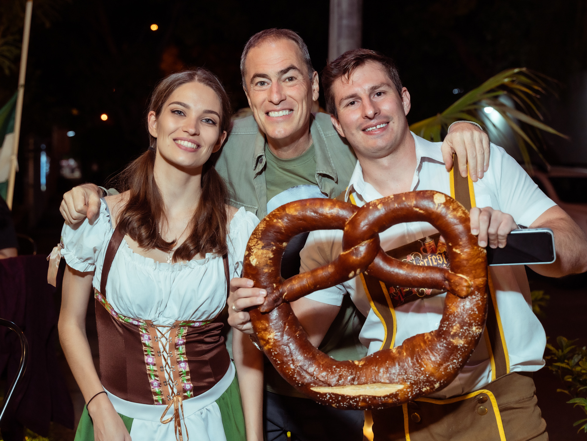 Equipe em traje típico alemão segurando um pretzel gigante
